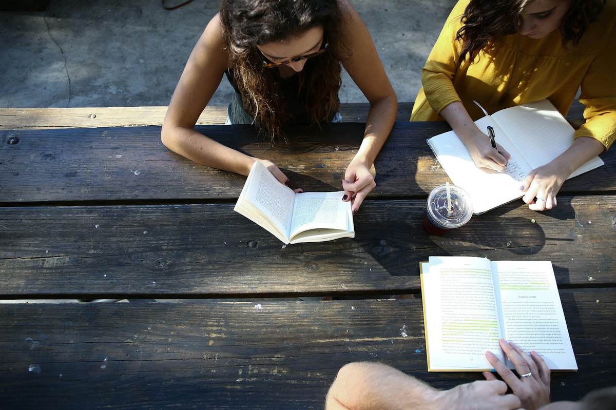 Students reading and taking notes at a wooden table