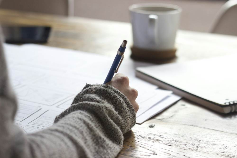 Hand writing notes next to a notebook